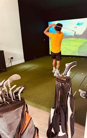 A man in a yellow shirt is playing a golf game on a screen.