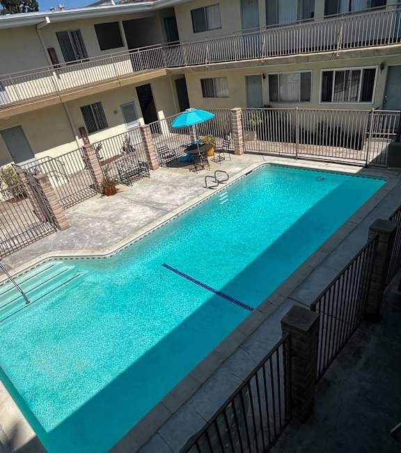 A pool with a hot tub and lounge chairs in front of a building.
