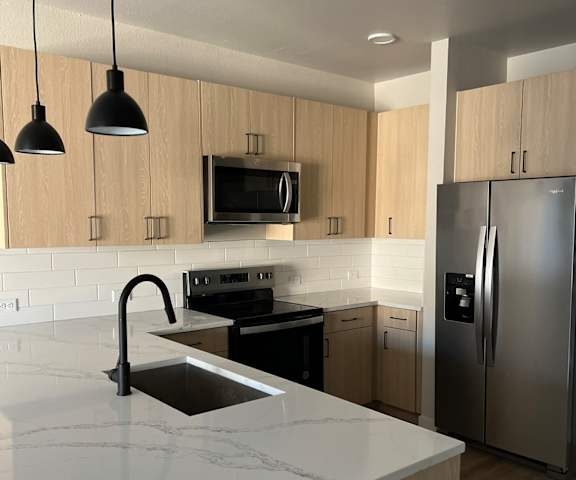 a kitchen with a marble counter top and a stainless steel refrigerator