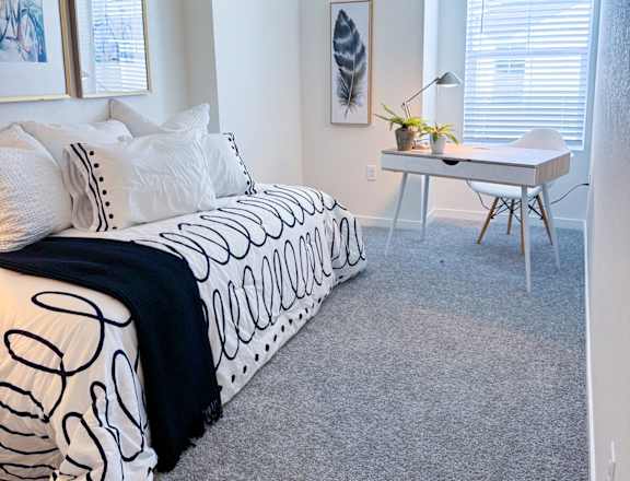 a bedroom with a bed and a desk and a window