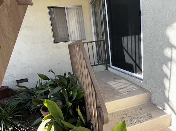 A balcony with a railing and steps leading up to a glass door.