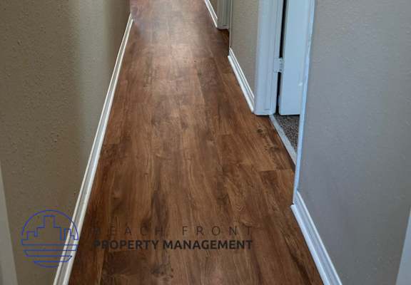 a long hallway with wood flooring and white walls
