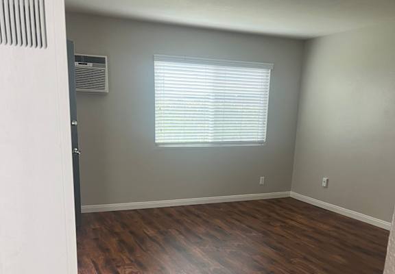 an empty room with wooden floors and a window