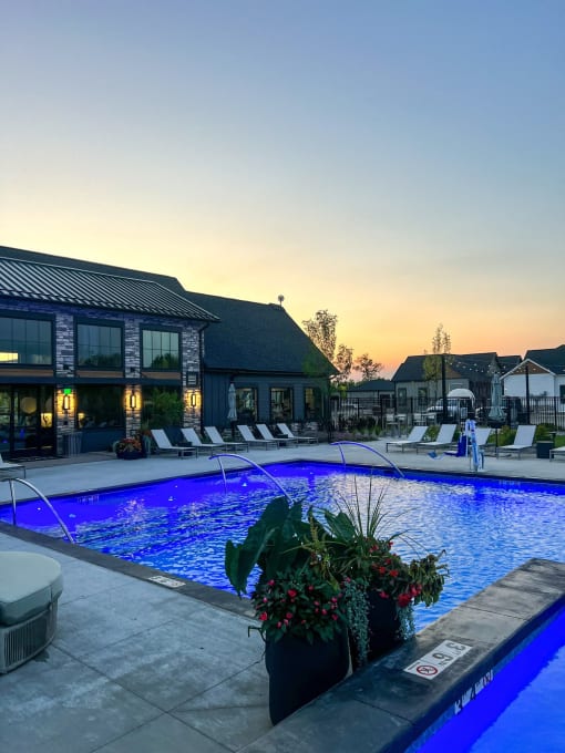 a swimming pool in front of a hotel at sunset at Slate at Fishers District, Fishers