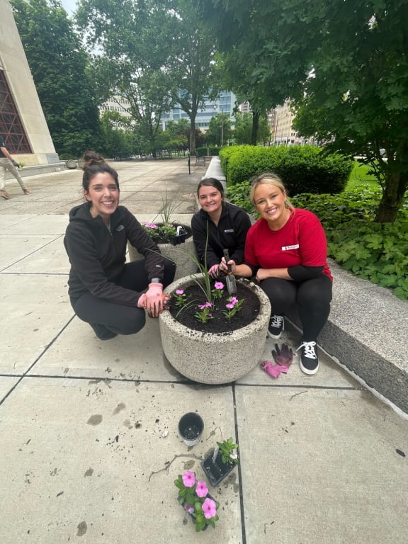 a group of women planting flowers in a planter