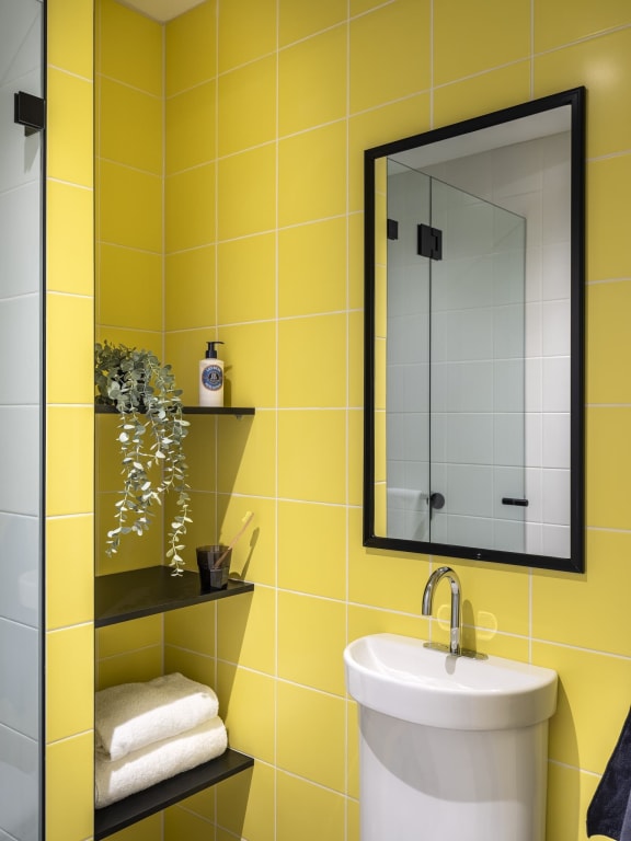 a yellow bathroom with a sink and a mirror