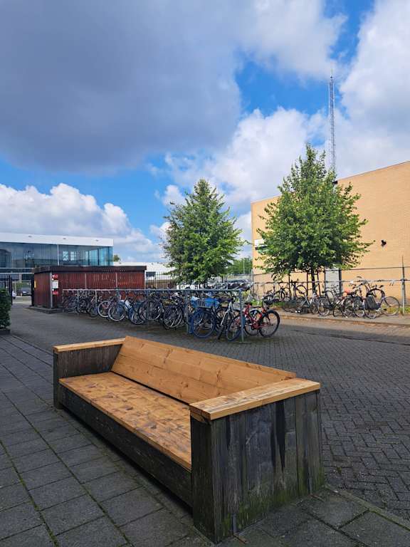 A wooden bench sits in front of a row of bicycles.