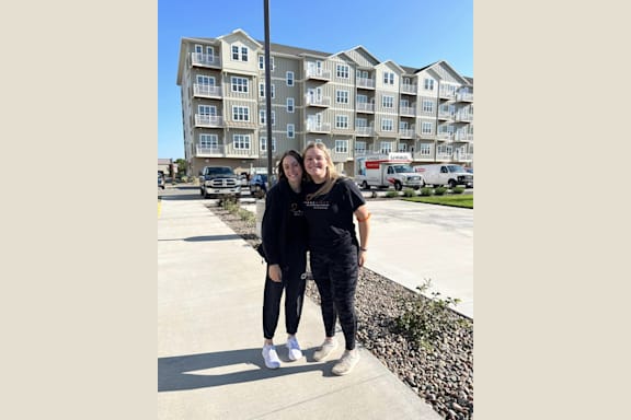 two women standing in front of an apartment building
