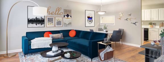 a living room with a blue couch and a kitchen in the background