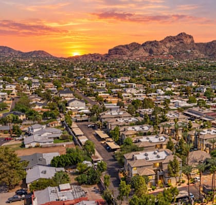 A sunset view of a city with a mountain in the background.