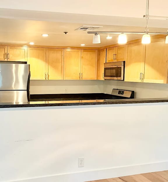 A kitchen with a white counter and wooden cabinets.