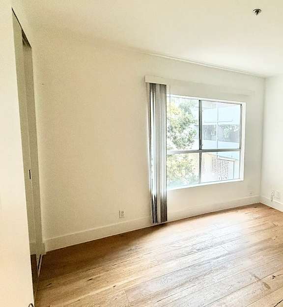A room with a window and wooden flooring.