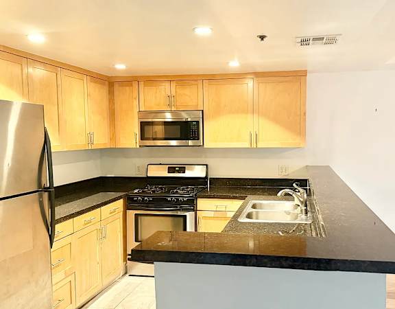A kitchen with wooden cabinets and a black countertop.