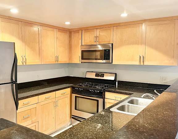 A kitchen with a stainless steel refrigerator and wooden cabinets.