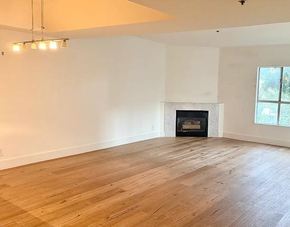 A large, empty room with a fireplace and wooden flooring.
