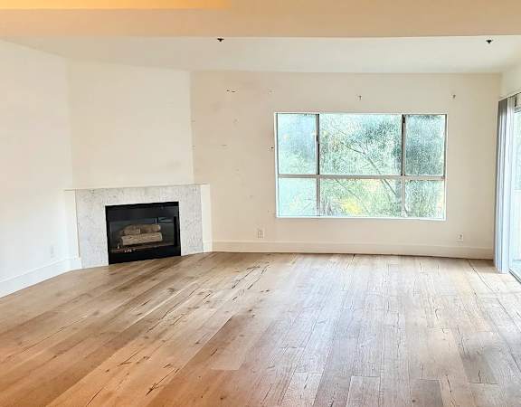 A large empty room with a fireplace and sliding glass doors.