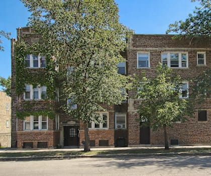 A brick building with a green awning sits on a street corner.