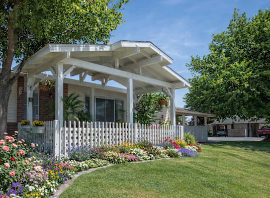 A white house with a porch and a white picket fence.