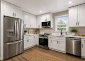 Thumbnail 4 of 4 - A modern kitchen with white cabinets and stainless steel appliances.