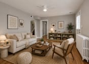 Thumbnail 2 of 4 - A living room with a white couch, a wooden coffee table, and a white radiator.