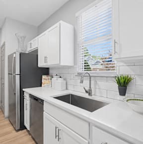A kitchen with white cabinets and a black fridge.