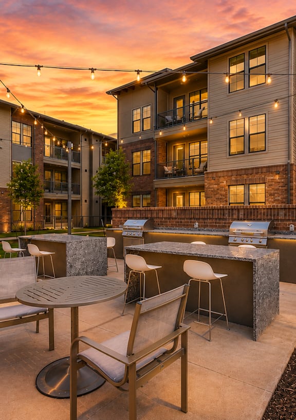 Outdoor grilling station and resident courtyard illuminated at sunset at One Preston Station Apartments.