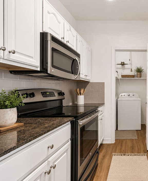 A modern kitchen with white cabinets and black countertops.