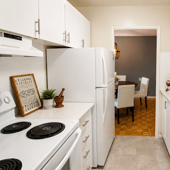 A kitchen with white appliances and cabinets.