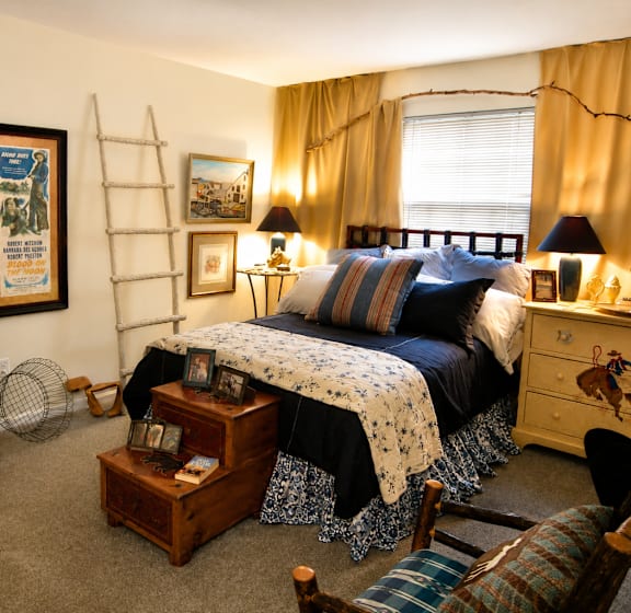 A bedroom with a bed, dresser, chair, and a mirror.
