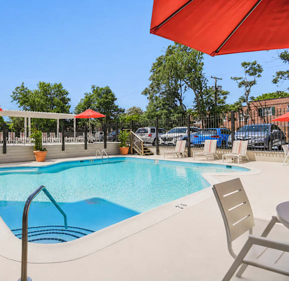 A pool area with sun loungers and a white pergola.