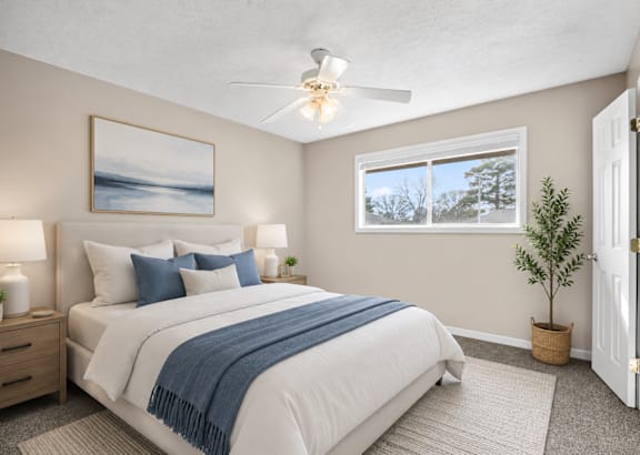 A bedroom with a bed, two lamps, a ceiling fan, and a painting on the wall.