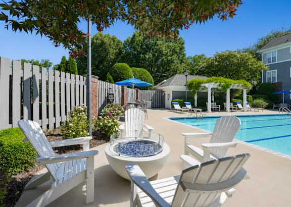 A poolside area with chairs and a fire pit.