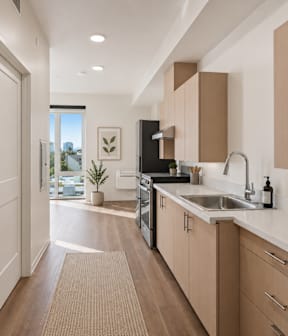 A modern studio kitchen with wooden cabinets and a white countertop.