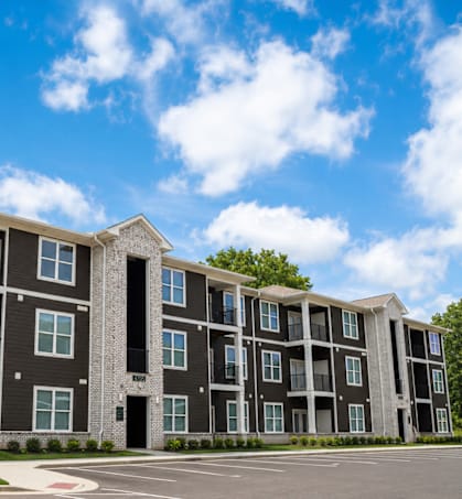A large, modern apartment building with multiple balconies and doors.