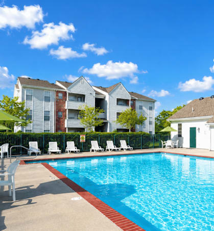 A swimming pool in front of a building with a white thatched roof.