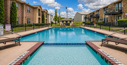 A swimming pool surrounded by apartment buildings on a sunny day.