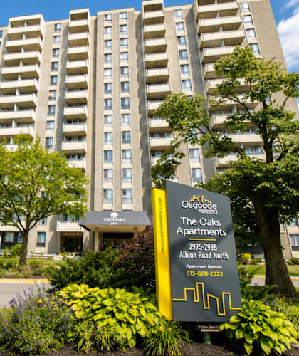 A tall building with a sign in front that says "The Oaks Apartments".