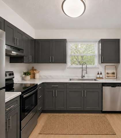 A kitchen with a refrigerator, sink, and cabinets.