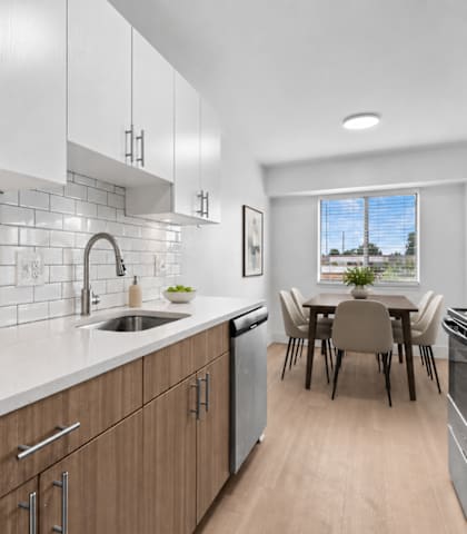 A modern kitchen with wooden cabinets and a dining table.