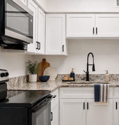 A kitchen with white cabinets and a black stove top oven.