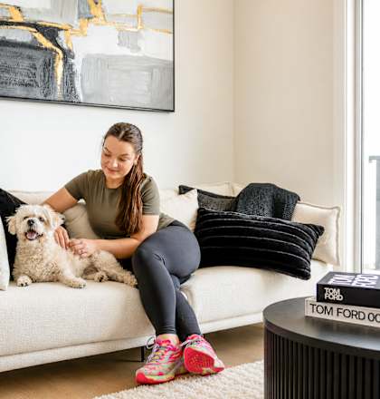 A woman is sitting on a couch with her dog.
