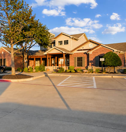 A parking lot in front of a building with a black car parked in the lot.