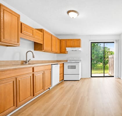 A kitchen with wooden cabinets and a white wall.