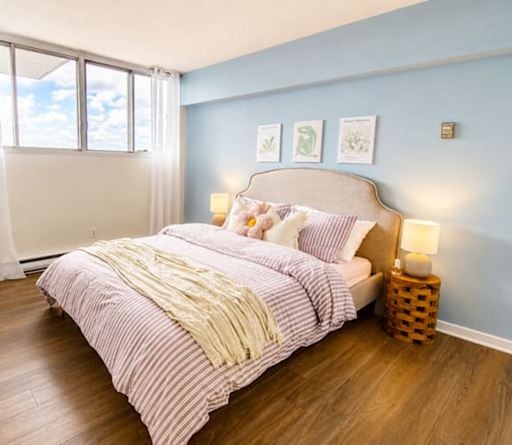 A bedroom with a bed, a lamp, and a potted plant.