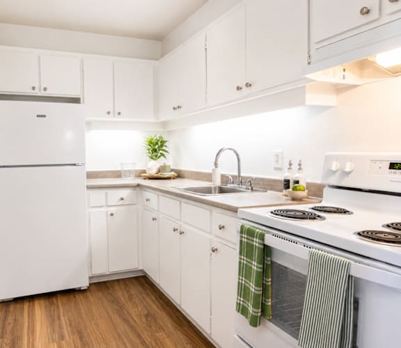 A white kitchen with wooden floors and white appliances.