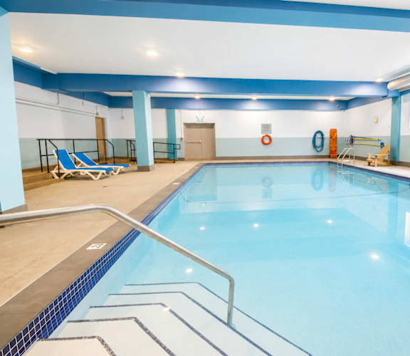 A large indoor swimming pool with a blue tiled edge and a metal ladder.