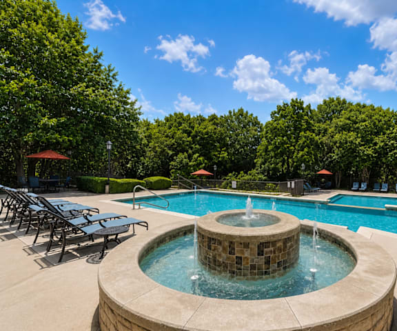 A large outdoor swimming pool with a hot tub in the middle.