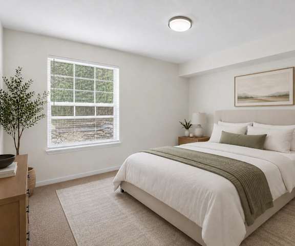 A bedroom with a large bed, nightstand, and a window with a view of a snowy landscape.