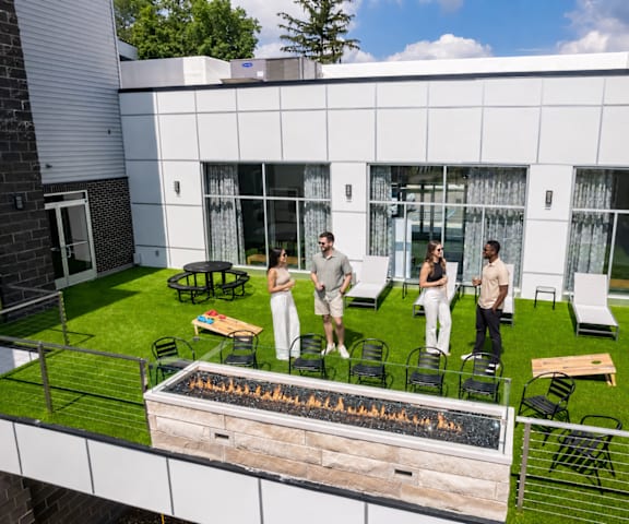 A group of people are gathered around a fire pit on a patio.