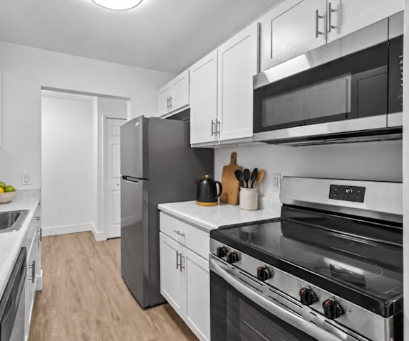 A kitchen with a black refrigerator and stove top oven.